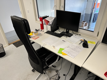 Höj- och sänkbart skrivbord med kontorsstol, datorskärm och tangentbord