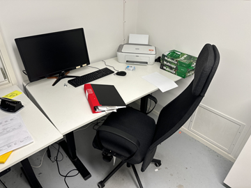 Höj- och sänkbart skrivbord med kontorsstol, datorskärm, tangentbord och datormus